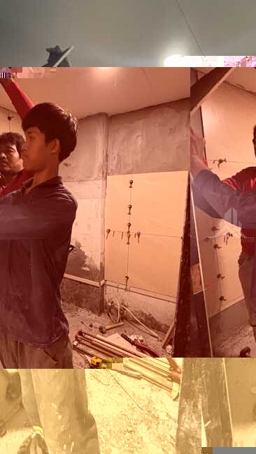 Two workers tiling a bathroom wall during a condo renovation in Jomtien