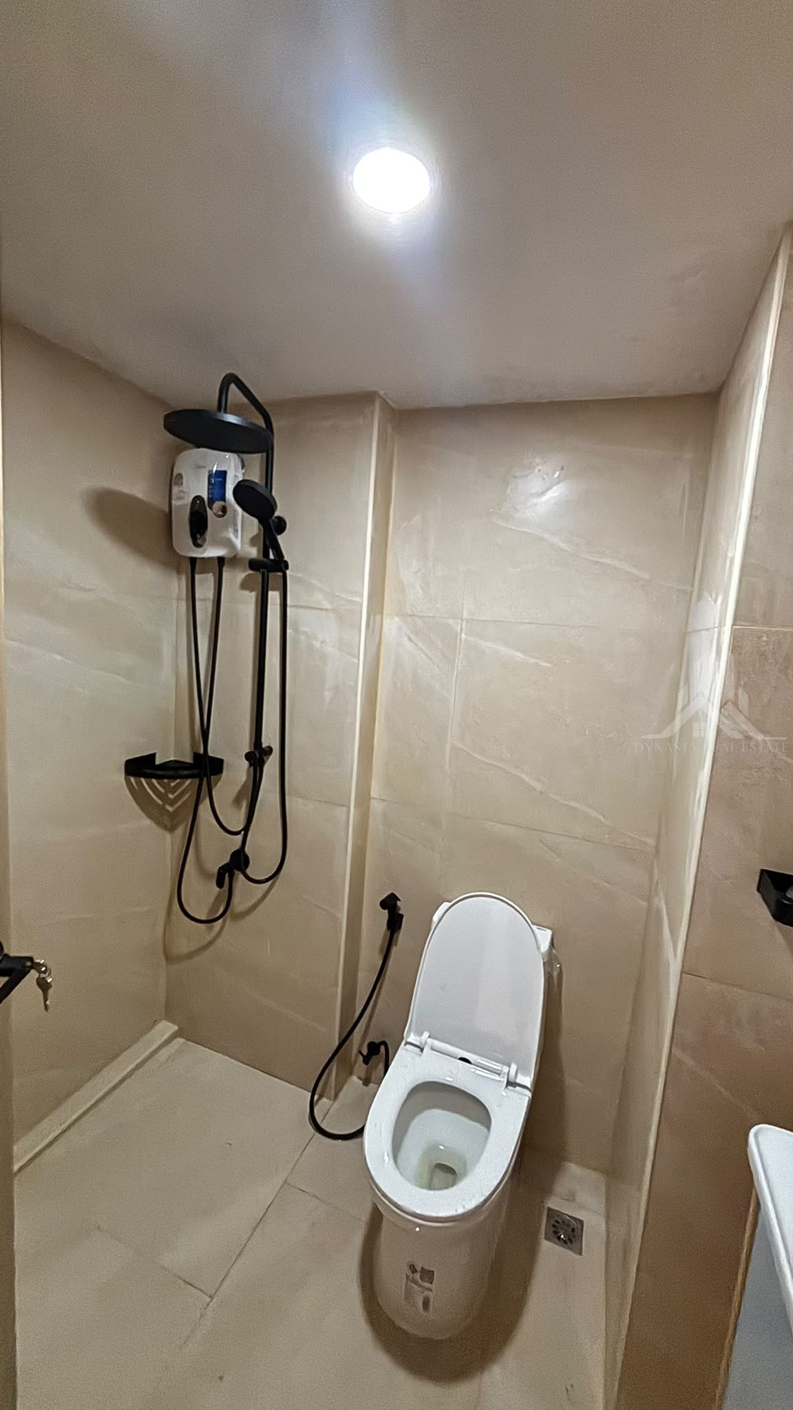 Black rain shower set with water heater and marble-look wall tiles in a renovated Chain Condo bathroom, Jomtien