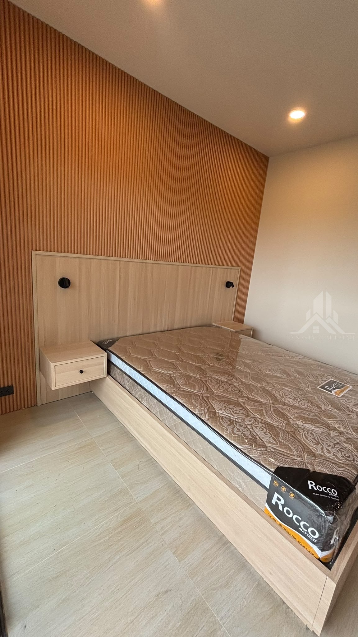 Built-in bed frame with wood headboard panel, reading lights and floating bedside drawers at Chain Condo, Jomtien