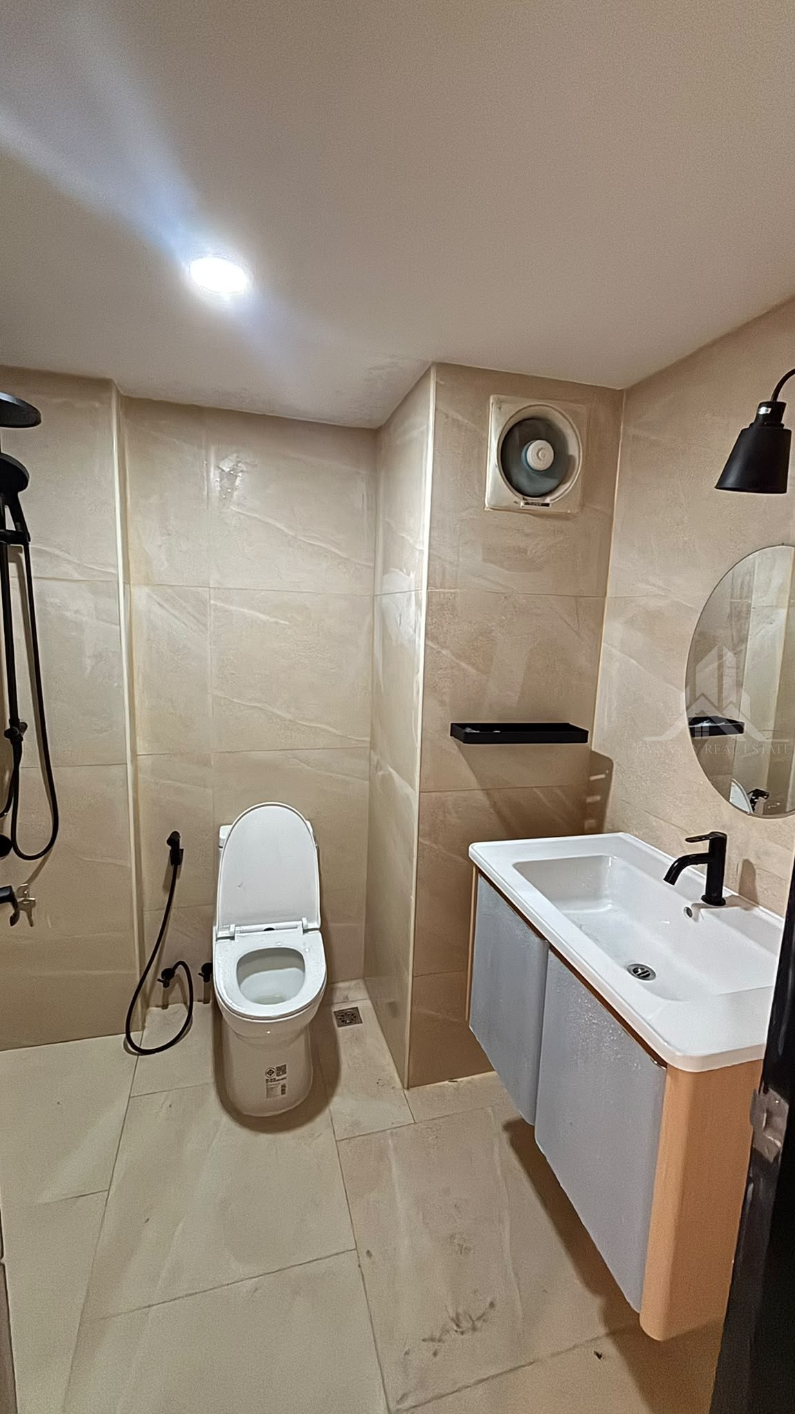 Renovated bathroom with marble-look tiles, wall-hung vanity basin and round mirror at Chain Condo, Jomtien